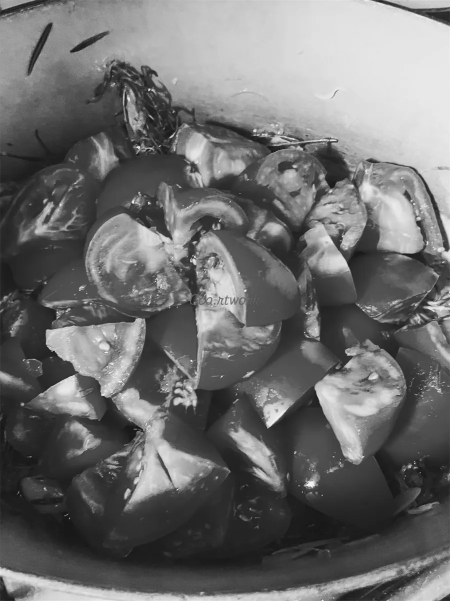 Tomates coupées en quartiers dans une marmite, vue en plongée, noir et blanc.